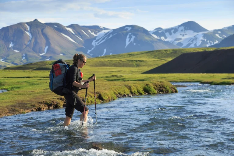Female hiker crossing a river on the Laugavegur trail on Iceland.