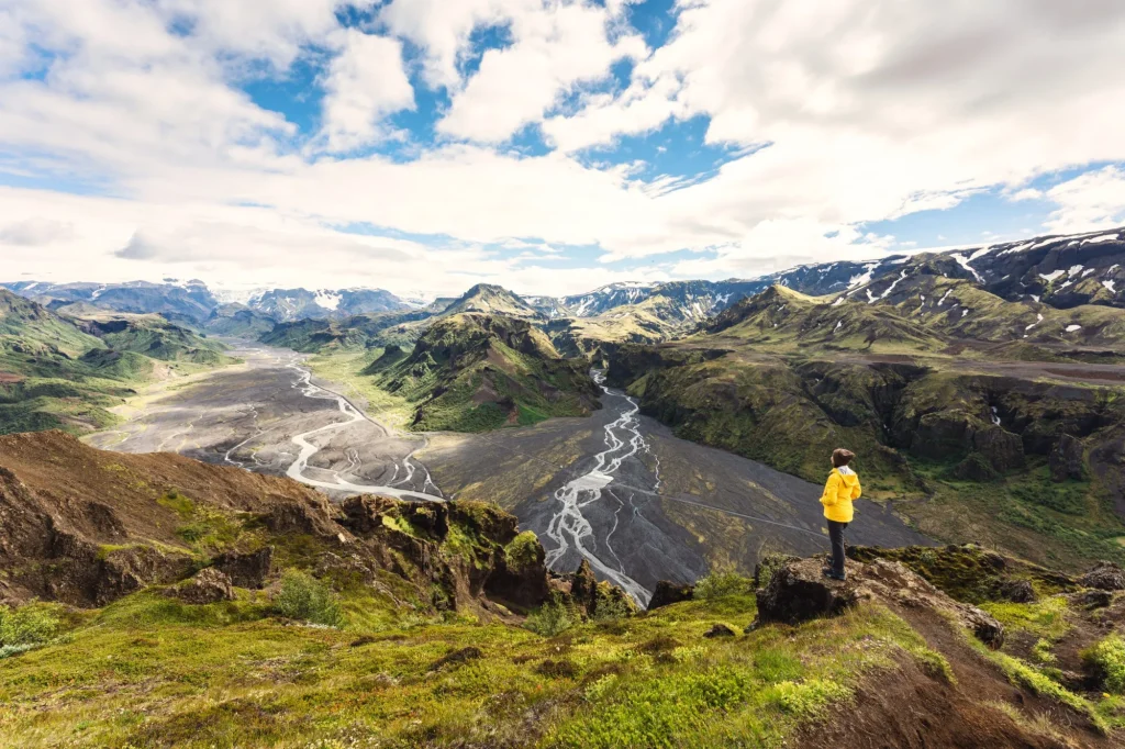Valahnúkur udsigtspunkt med kvindelig vandrer stående på toppen og Krossa-floden strømmende igennem i det islandske højland ved Thórsmörk, Island